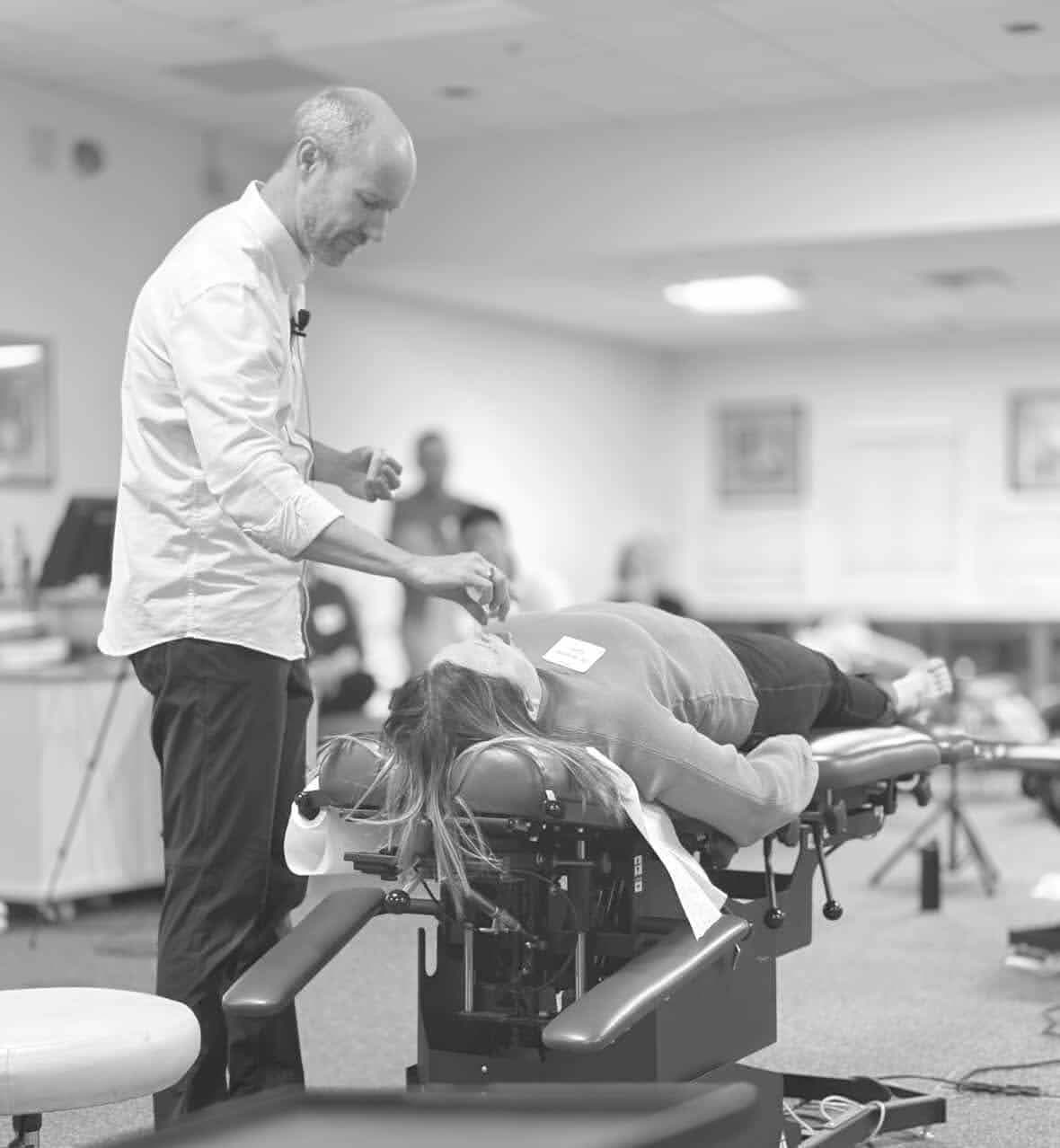 Dr. Rostenberg demonstrating chiropractic technique on a patient during a clinical training workshop — practitioners observing